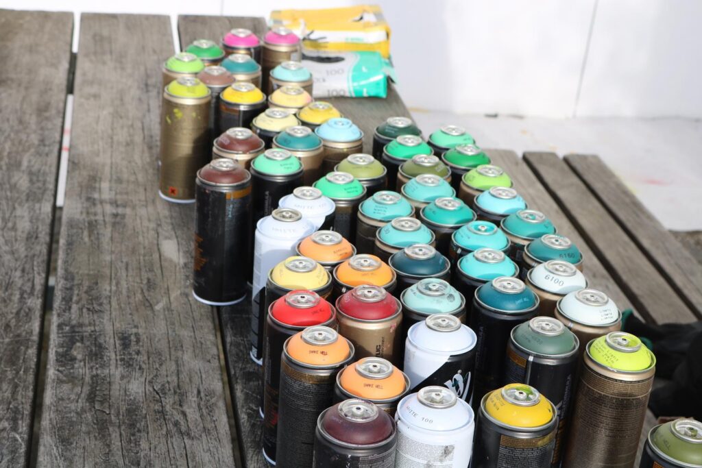 Eine Sammlung von farbigen Spraydosen auf einem Holztisch.