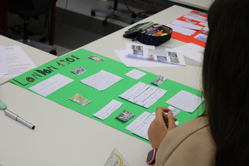 Eine Schülerin arbeitet an einem Plakat mit verschiedenen Informationen und Bildern.
