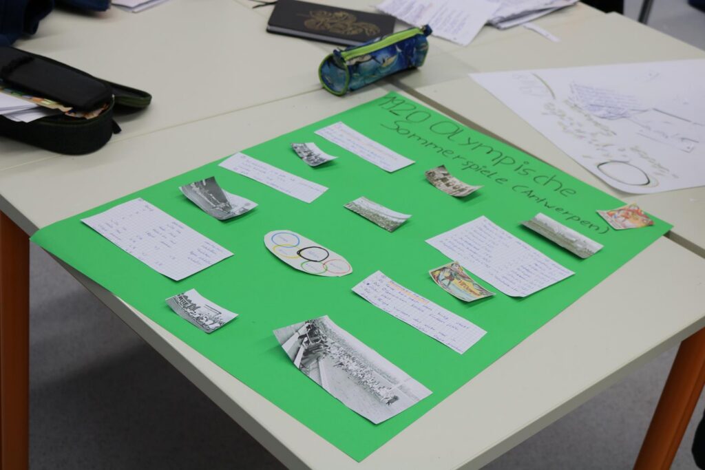 Ein grünes Plakat mit verschiedenen Texten und Bildern auf einem Tisch.