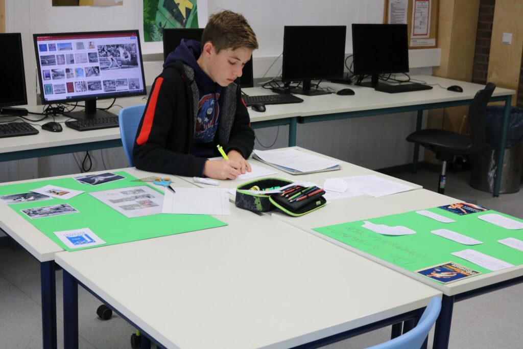 Schüler arbeitet an einem Tisch in einem Computerraum.