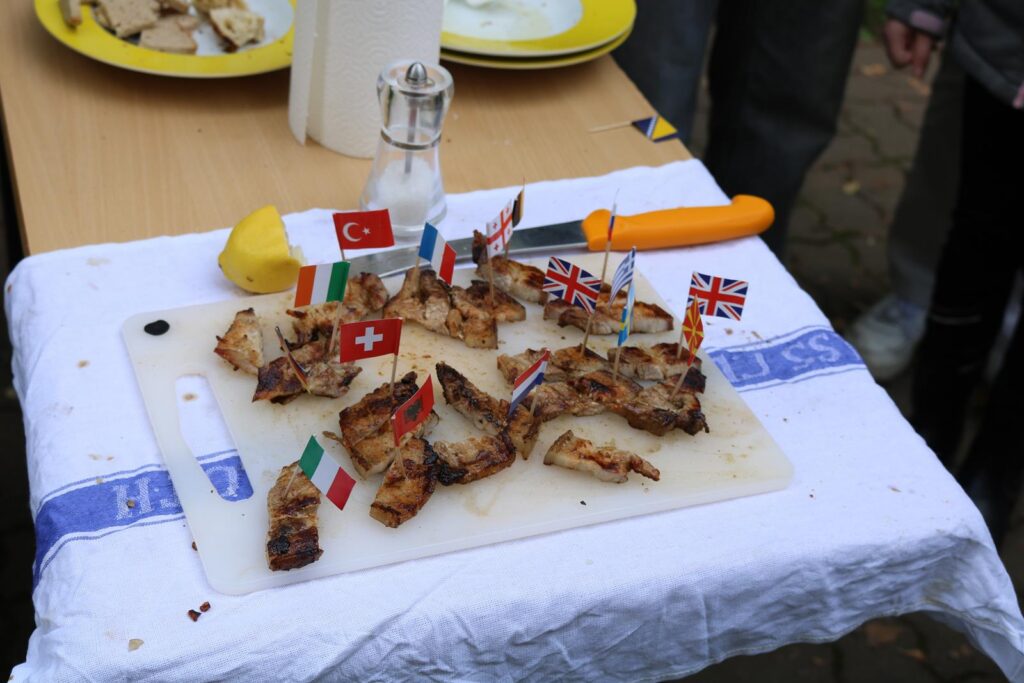 Auf einem Tisch liegt ein Schneidebrett mit gegrilltem Brot, dekoriert mit Miniaturflaggen.