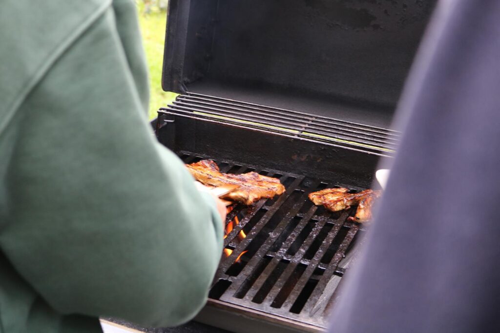 Person beim Grillen von Fleisch auf einem Grill.