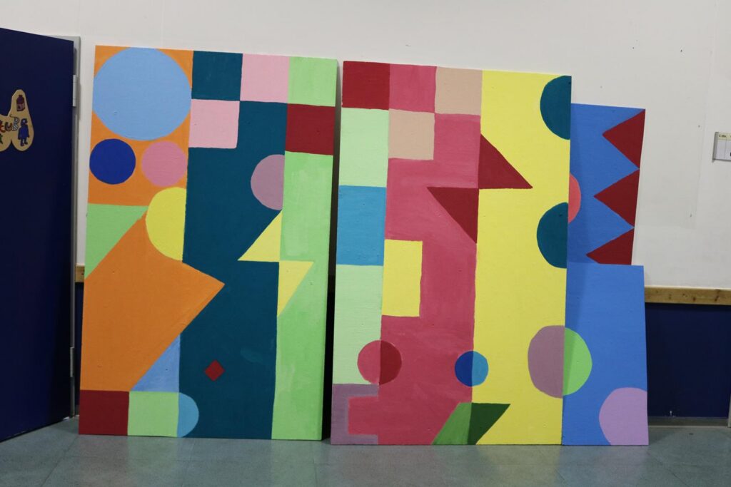 Bunte geometrische Wandkunst mit verschiedenen Formen und Farben.