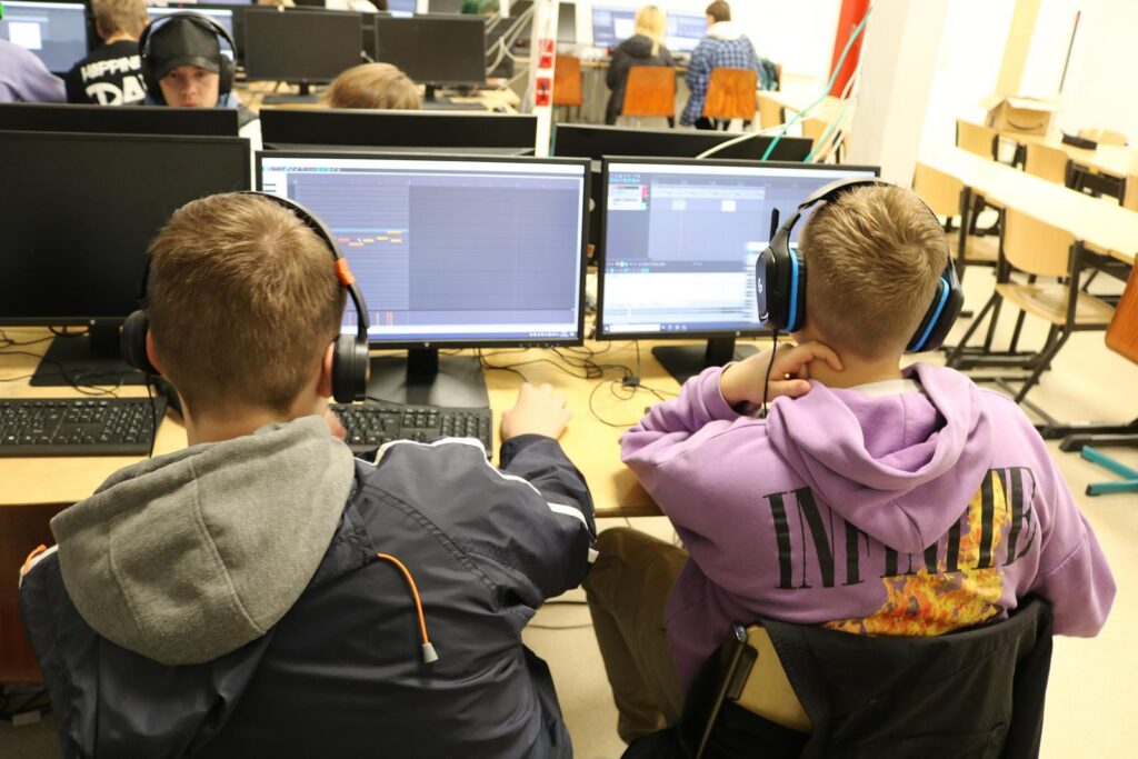Schüler am Computer, arbeiten mit Headsets und Software.