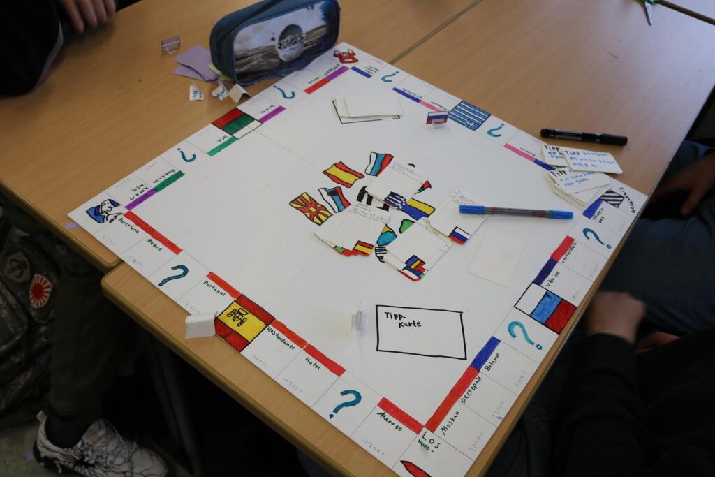 Brettspiel auf einem Tisch mit farbigen Karten und Stiften.