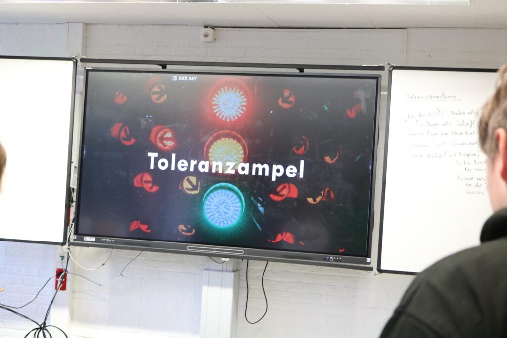 Das Bild zeigt einen Bildschirm mit der Aufschrift "Toleranzampel" und bunten Lichtern.