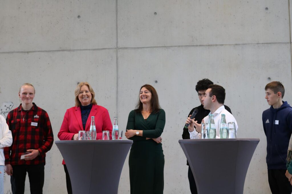 Gruppenfoto von Personen an Stehtischen in einem modernen Raum.