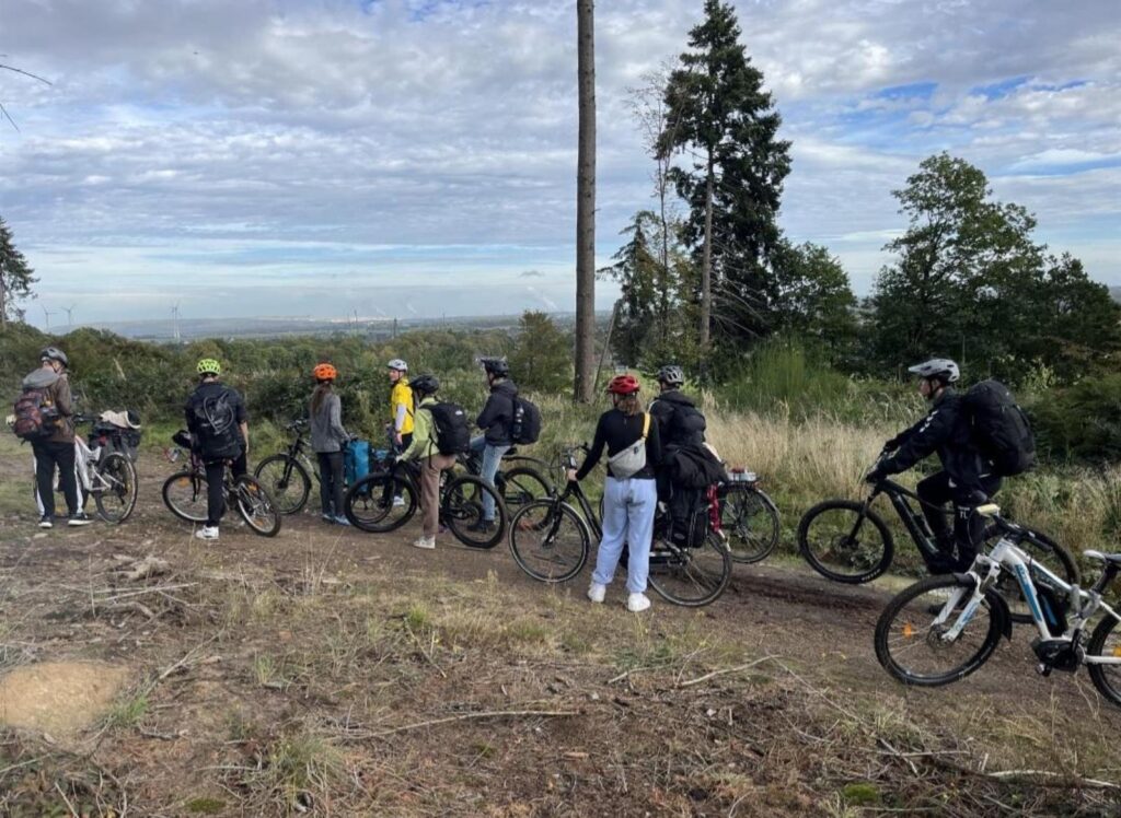 Gruppe von Radfahrern auf einem Waldweg mit Blick auf die Landschaft.