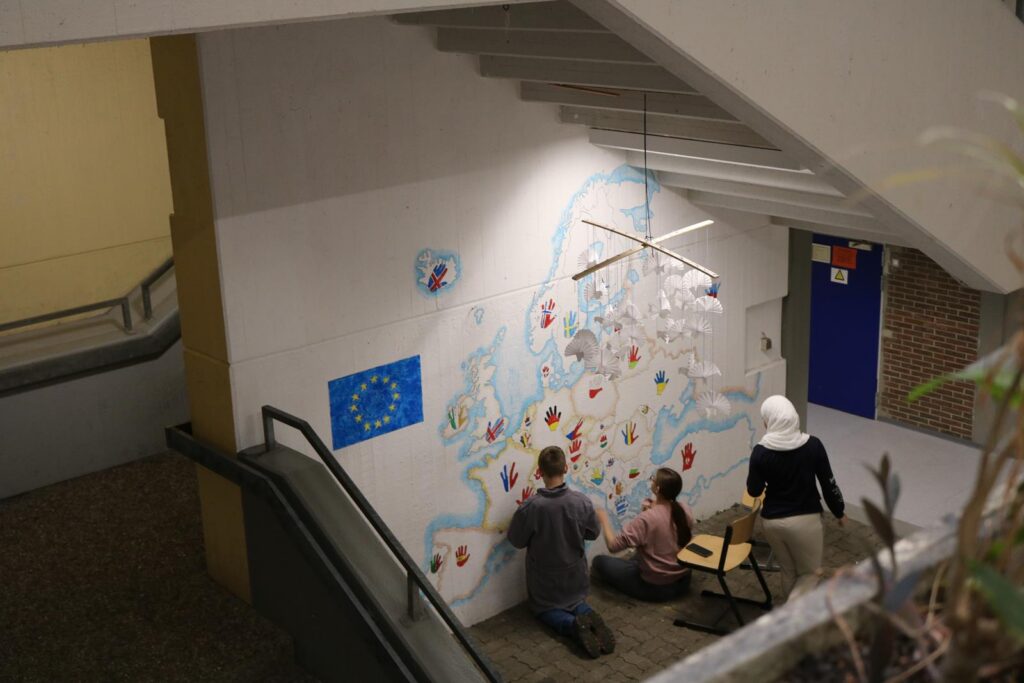 Schüler gestalten eine Wandmalerei von Europa in einem Schulgebäude.