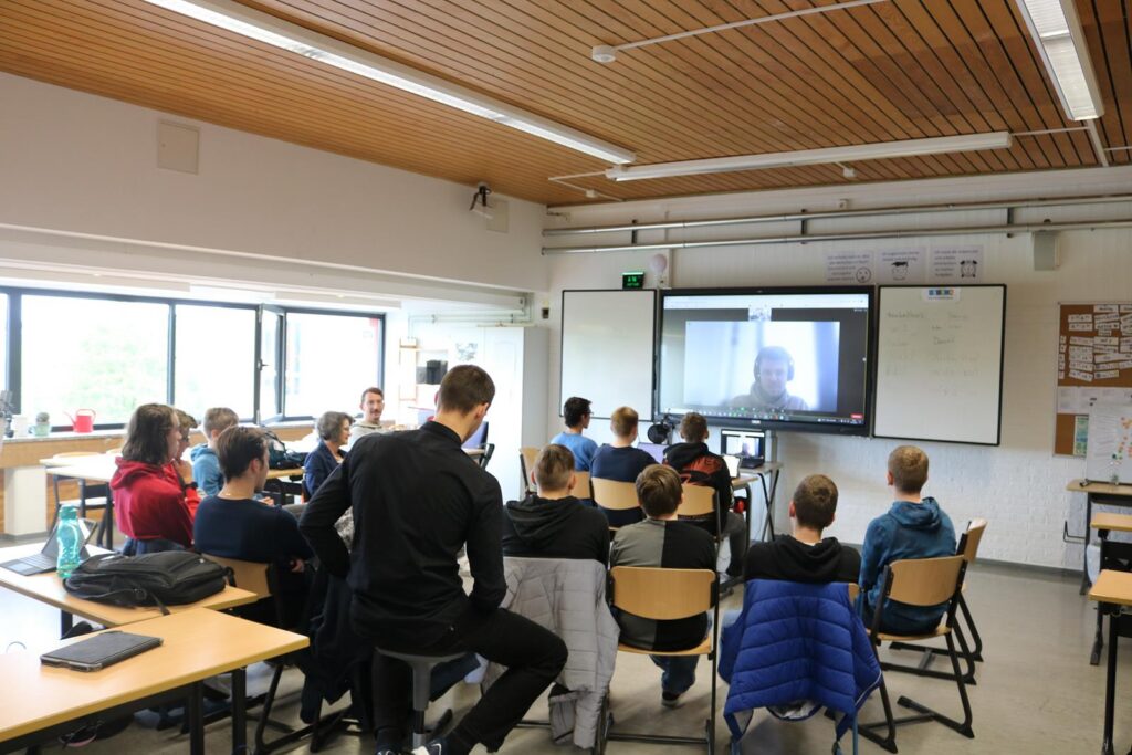 Schüler sitzen im Klassenzimmer und nehmen an einer Videokonferenz teil.