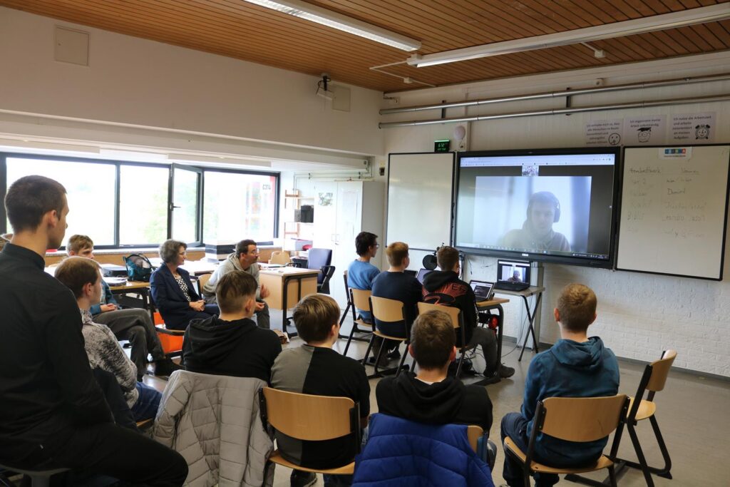 Schüler sitzen im Klassenzimmer und sehen eine Video-Präsentation an.