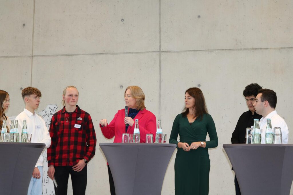 Personen stehen an Stehtischen und diskutieren miteinander.