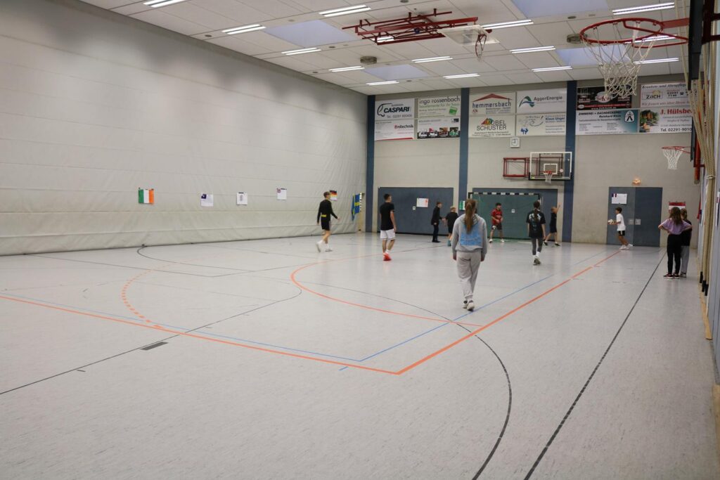 Sporthalle mit Schülern beim Basketballspielen und Training.