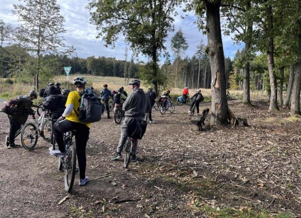 Gruppe von Radfahrern auf einem Waldweg, Bäume im Hintergrund.