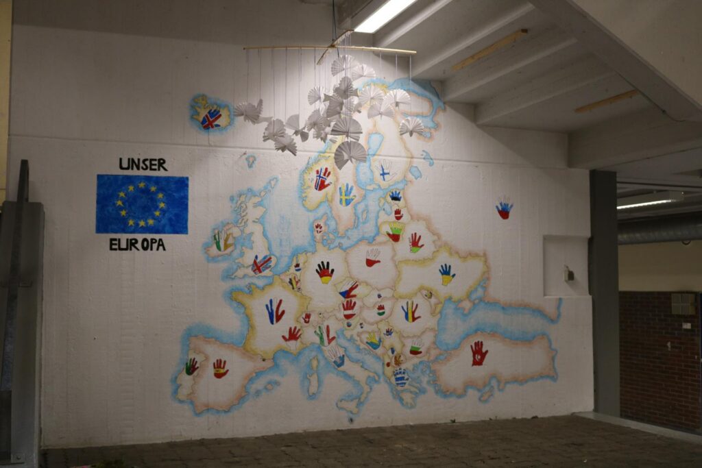 Wandmalerei einer Europakarte mit bunten Symbolen.