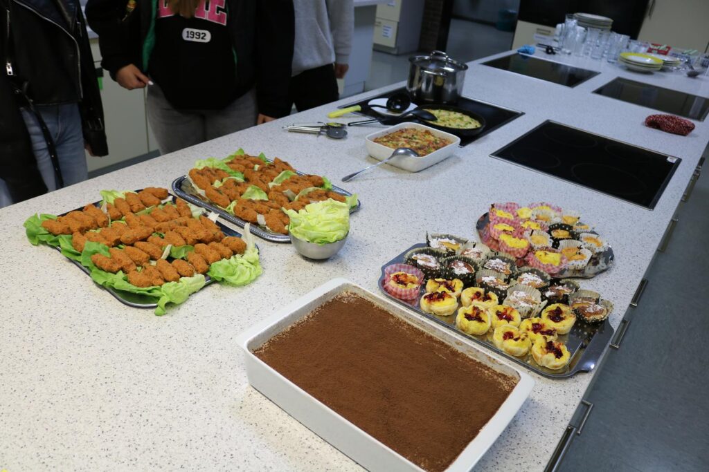 Buffet mit verschiedenen Speisen, darunter Snacks und Desserts auf einem Tisch.