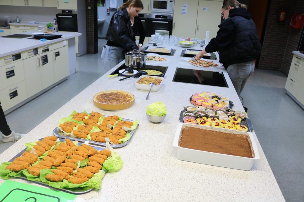 Küchenarbeitsplatz mit verschiedenen Speisen und Desserts auf dem Tisch.