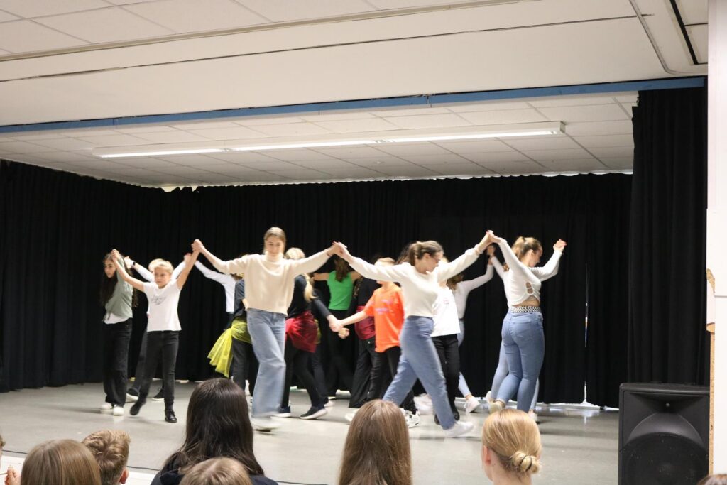 Tanzende Schüler präsentieren eine Choreografie auf der Bühne.