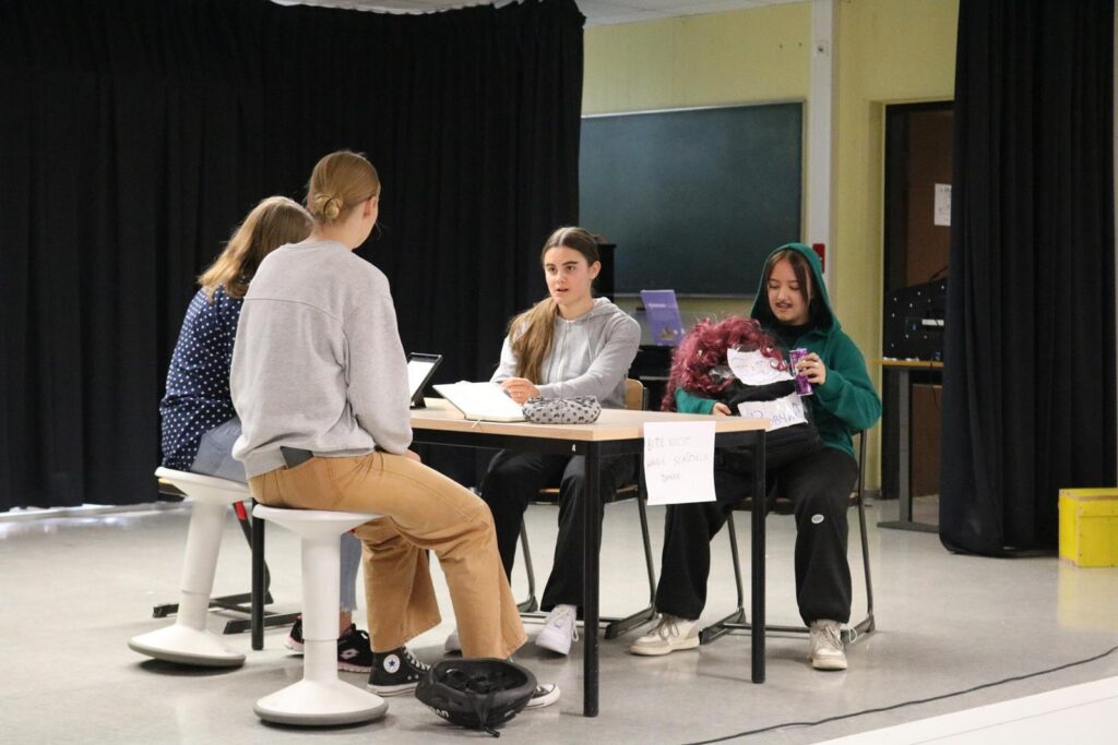 Schüler diskutieren an einem Tisch in einem Klassenraum.
