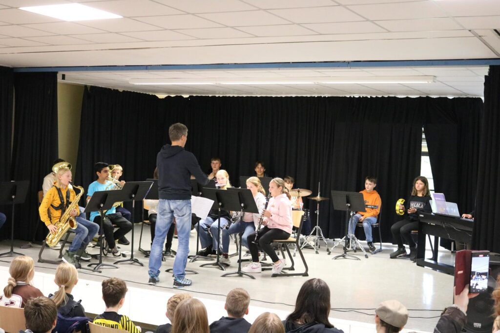 Schüler spielen in einem Konzert unter der Leitung eines Lehrers.