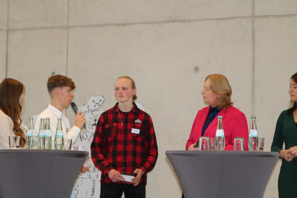 Eine Gruppe von Personen steht an Stehtischen und diskutiert.