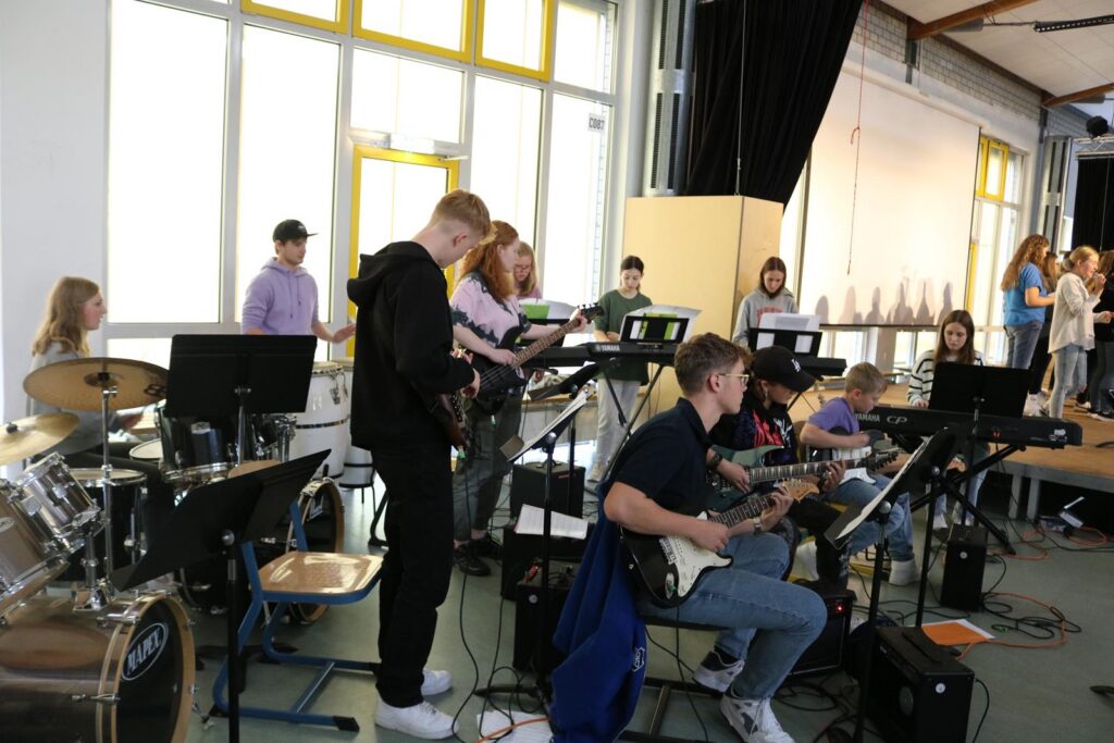 Schülerband spielt Instrumente in einem Klassenraum.