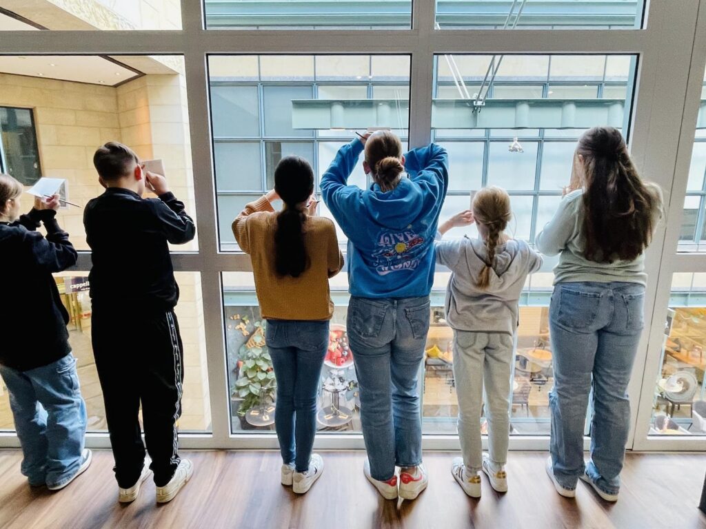 Sechs Schüler stehen am Fenster und schauen nach draußen.