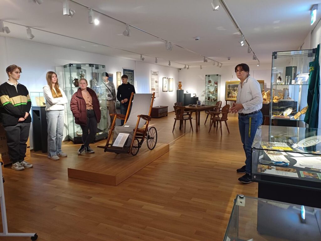Eine Gruppe von Personen hört in einem Museum einer Erläuterung zu.