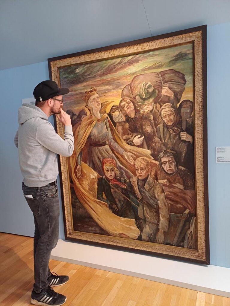 Besucher steht nachdenklich vor einem großen Gemälde in einem Museum.