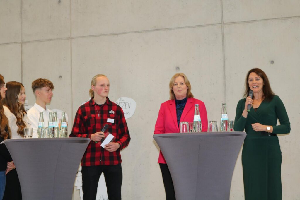 Gruppendiskussion mit mehreren Personen und zwei Rednerinnen am Mikrofon.