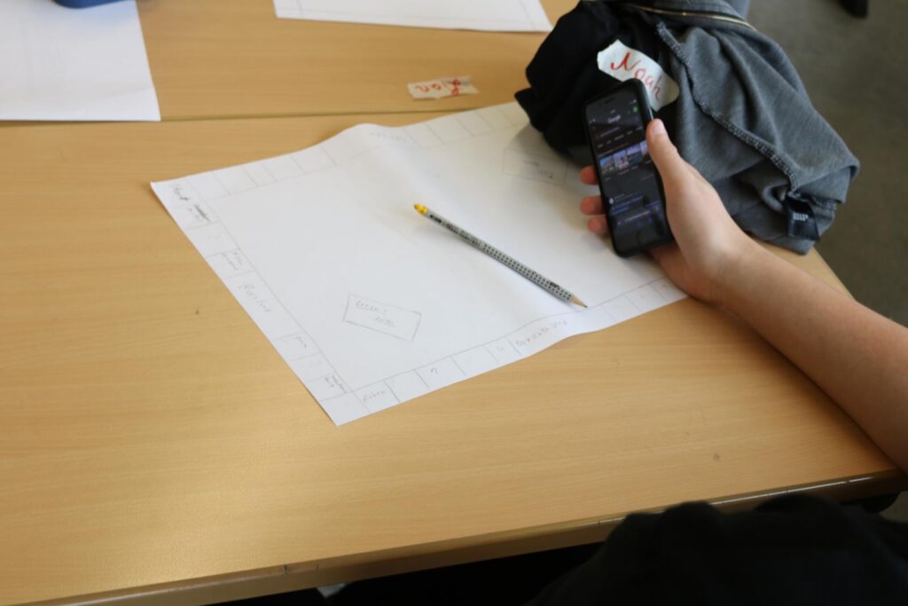 Ein Tisch mit einem Blatt Papier, einem Bleistift und einem Handy in der Hand.