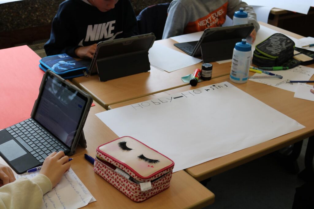 Schüler arbeiten an Tischen mit Tablets, Stiften und einem leeren Arbeitsblatt.