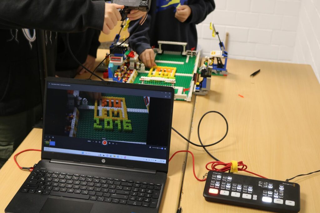 Ein Schüler programmiert ein LEGO-Projekt mit Laptop und Kamera.
