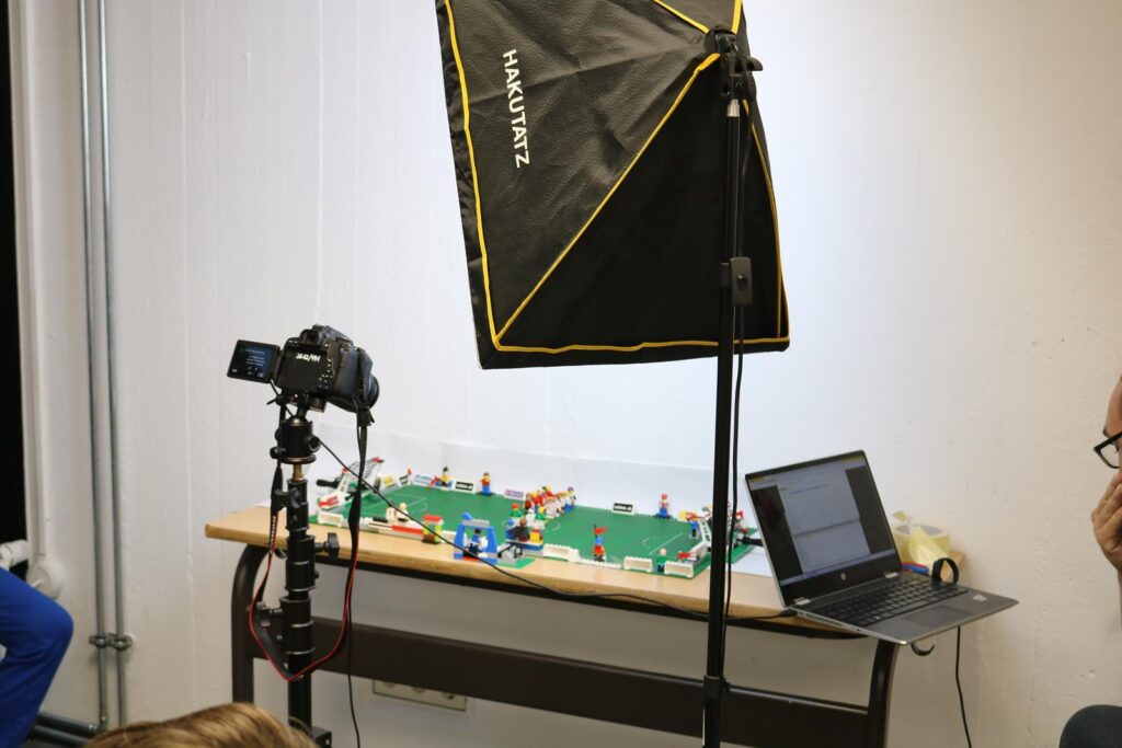 Fotostudio mit Kamera, Licht und LEGO-Modell auf einem Tisch.