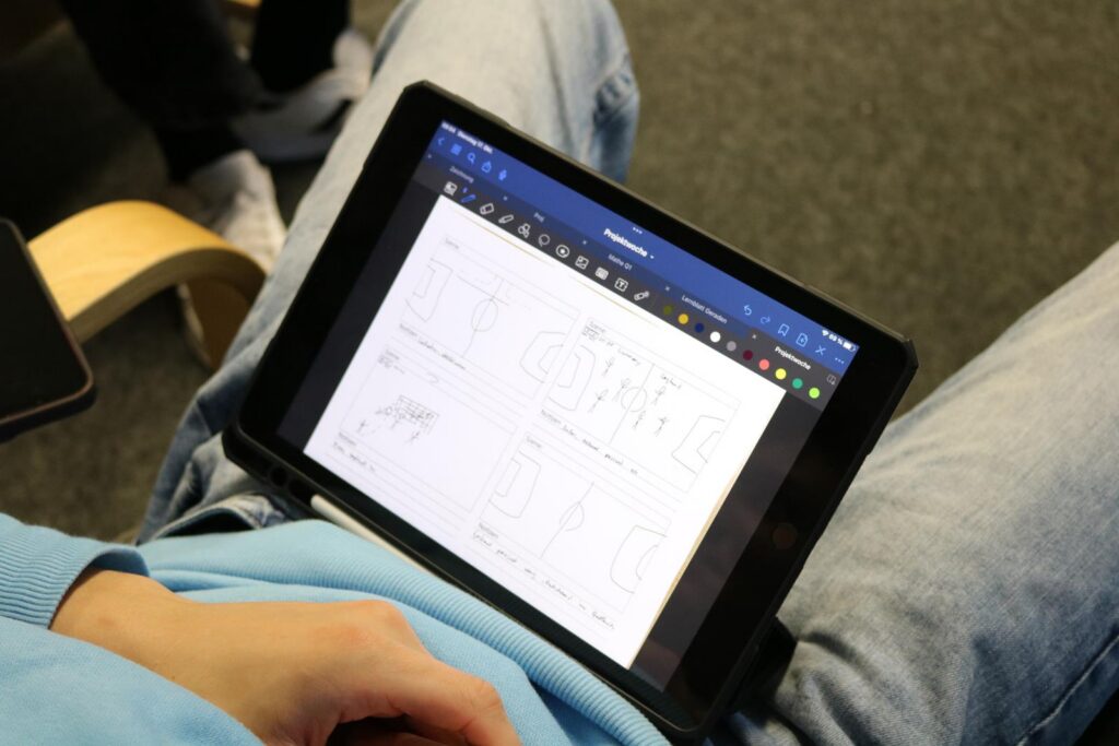 Ein Schüler hält ein Tablet mit skizzierten Zeichnungen.
