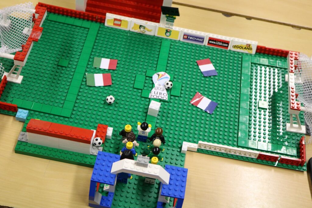 Eine LEGO-Nachbildung eines Fußballfeldes mit Spielfiguren und Flaggen.