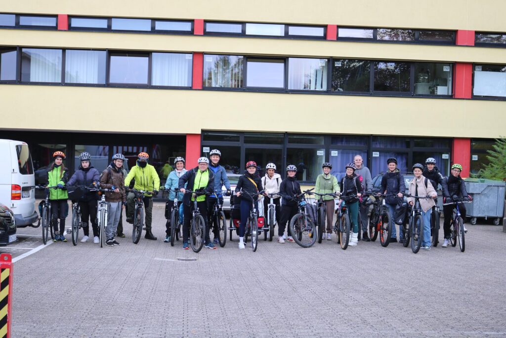 Gruppe von Radfahrern steht vor einem Gebäude mit Fahrrädern.