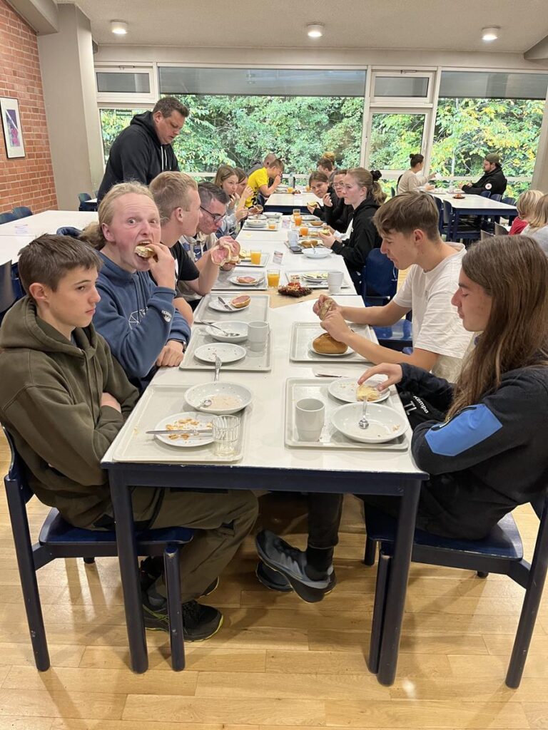 Schüler sitzen an Tischen und essen gemeinsam in einem Speiseraum.