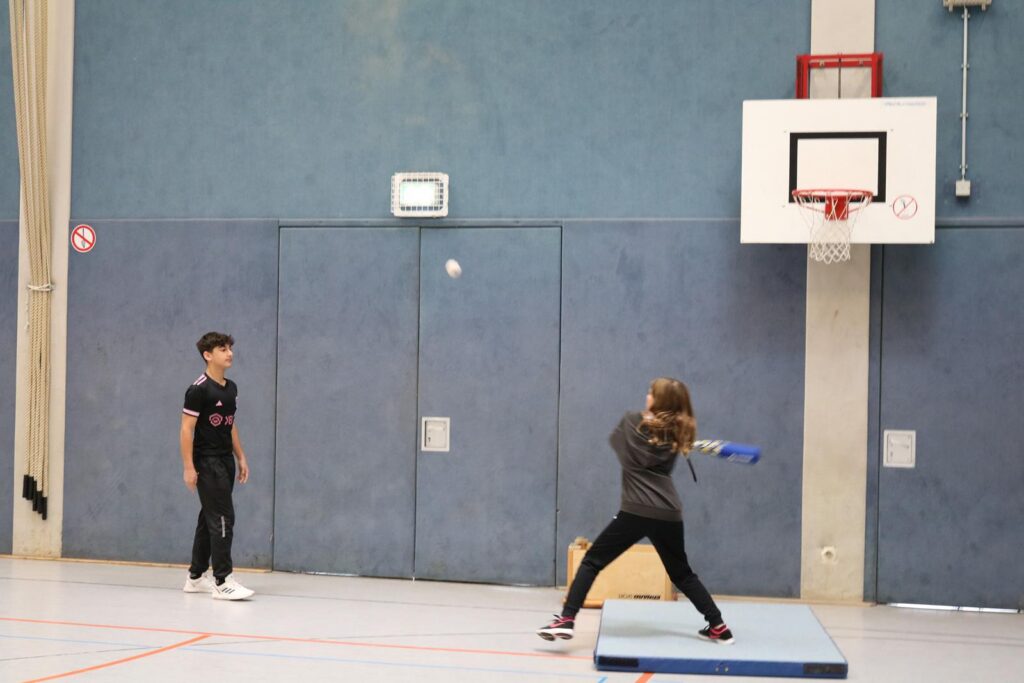 Schüler werfen einen Ball während des Sportunterrichts in einer Turnhalle.