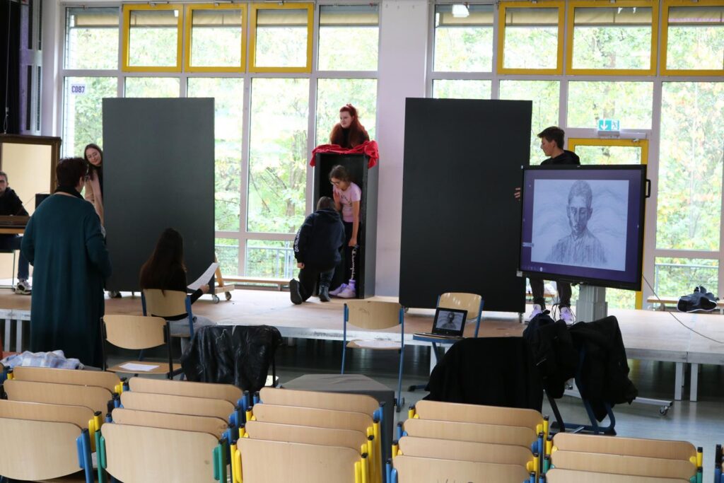 Schüler*innen präsentieren Kunstwerke in einem lichtdurchfluteten Raum.
