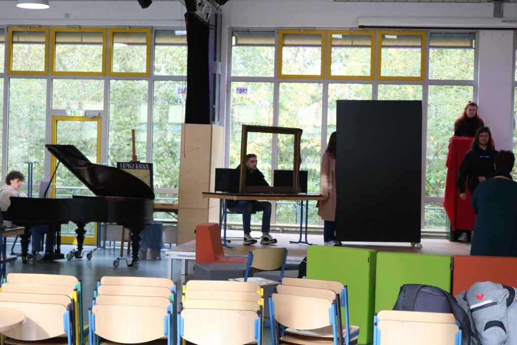 Schüler arbeiten an einer Bühne mit Klavier, Kulissen und Stühlen.