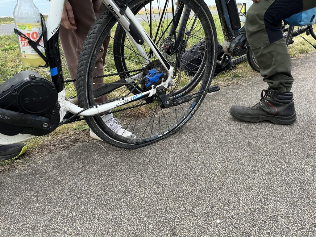 Zwei Personen stehen neben einem Fahrrad mit einem plattgewalzten Reifen.