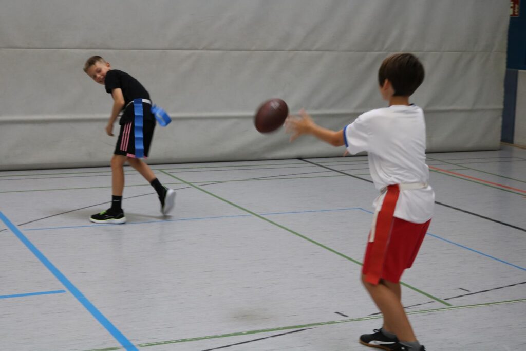 Zwei Jungen spielen in einer Halle mit einem Sportball.