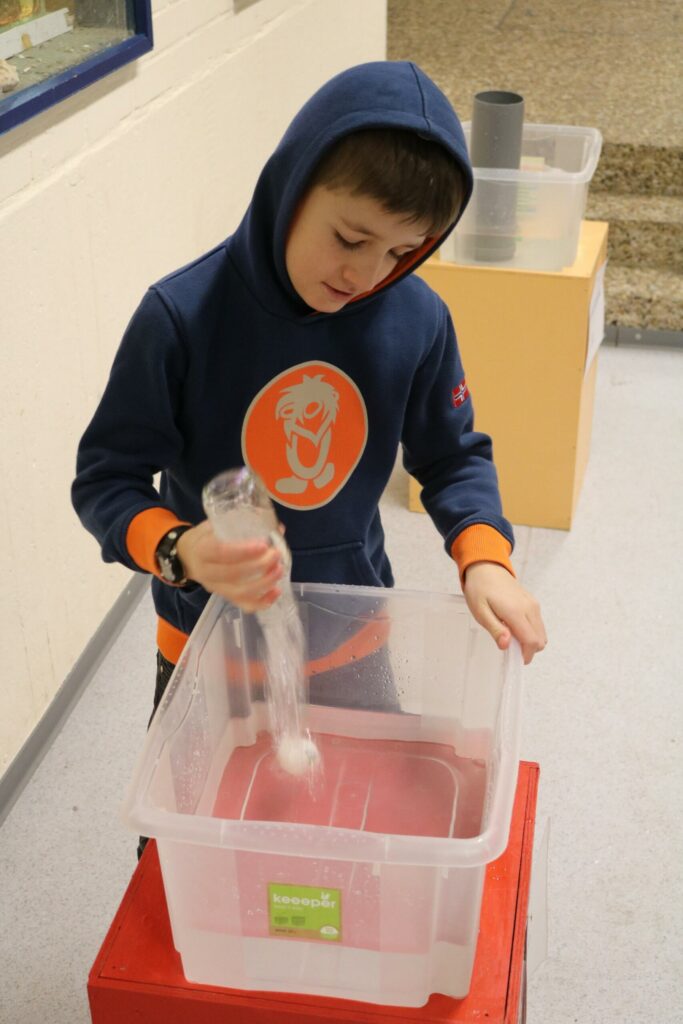 Ein Junge experimentiert mit Wasser in einer transparenten Box.