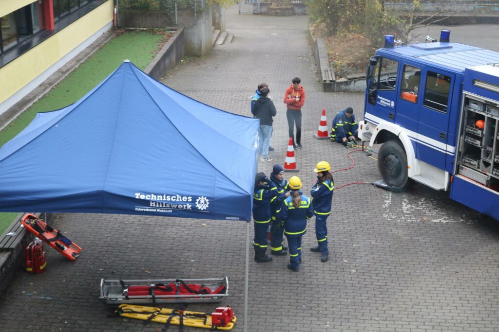 Rettungskräfte üben mit Feuerwehrfahrzeug und Ausrüstung unter einem Zelt.