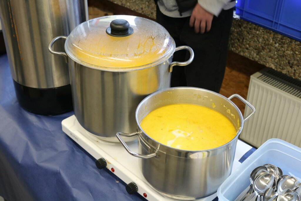 Zwei Kochtöpfe mit gelber Suppe auf einem Tisch.