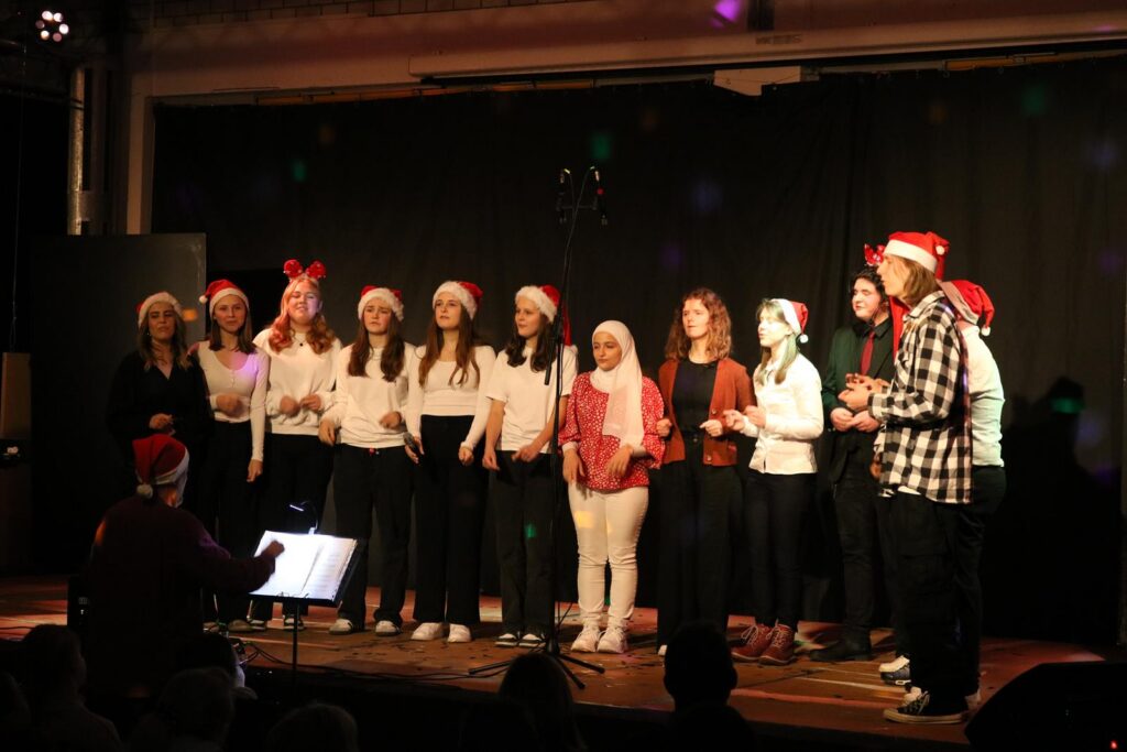 Schüler singen im Chor, alle tragen Weihnachtsmützen.