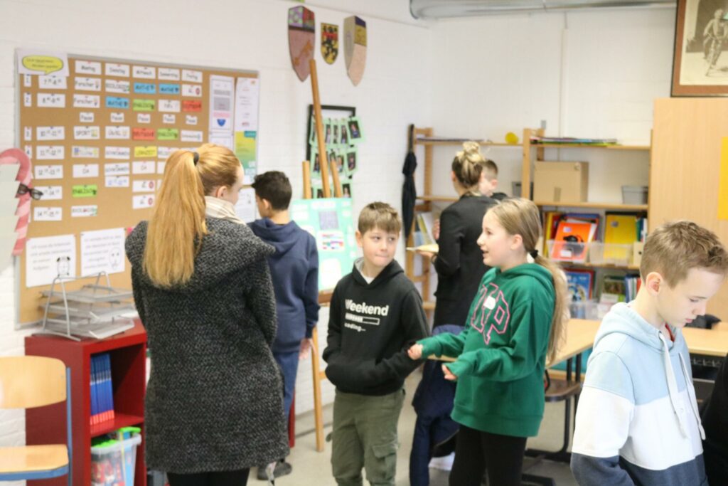 Schülerinnen und Schüler stehen in einem Klassenzimmer und unterhalten sich.