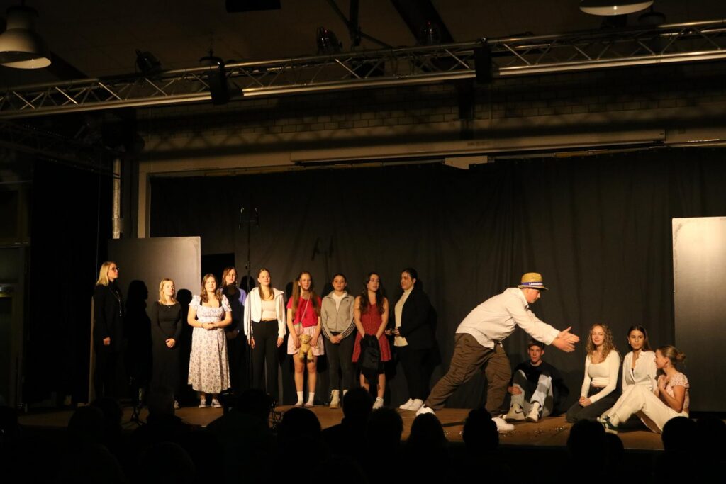Theateraufführung mit mehreren Schauspielern auf der Bühne.