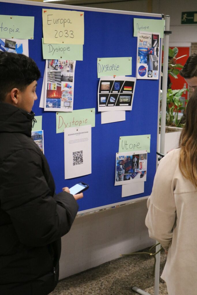 Schüler betrachten Ausstellungsplakate an einer Präsentationswand.